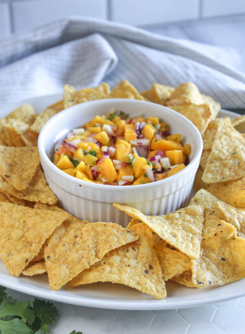 mango salsa with chips on a white plat