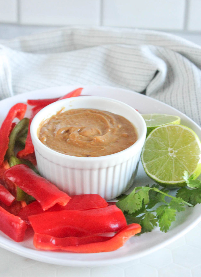 peanut sauce on a plate with limes and peppers