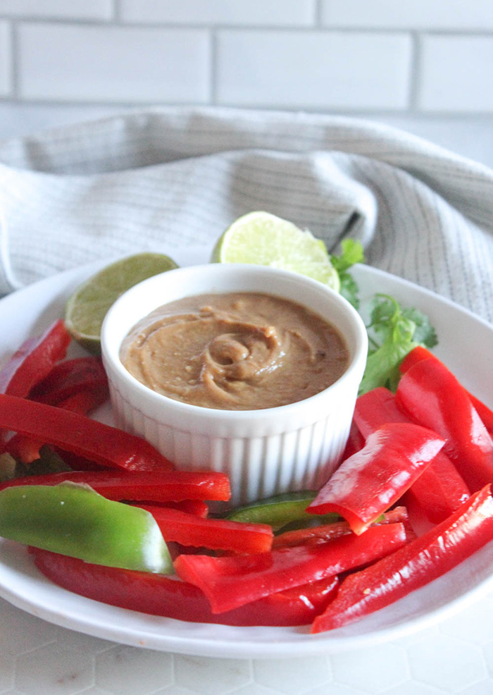 peanut sauce on a plate with peppers and limes