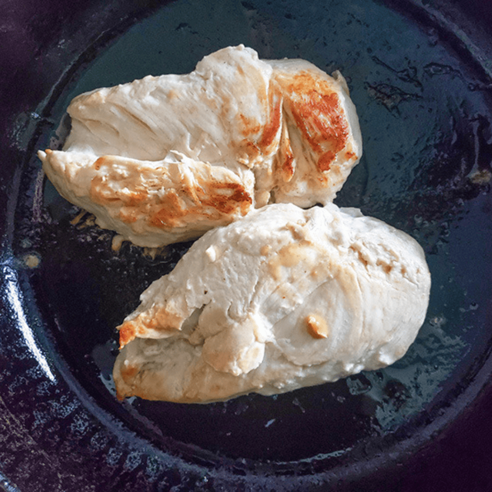 two boneless chicken breasts in a heavy skillet 