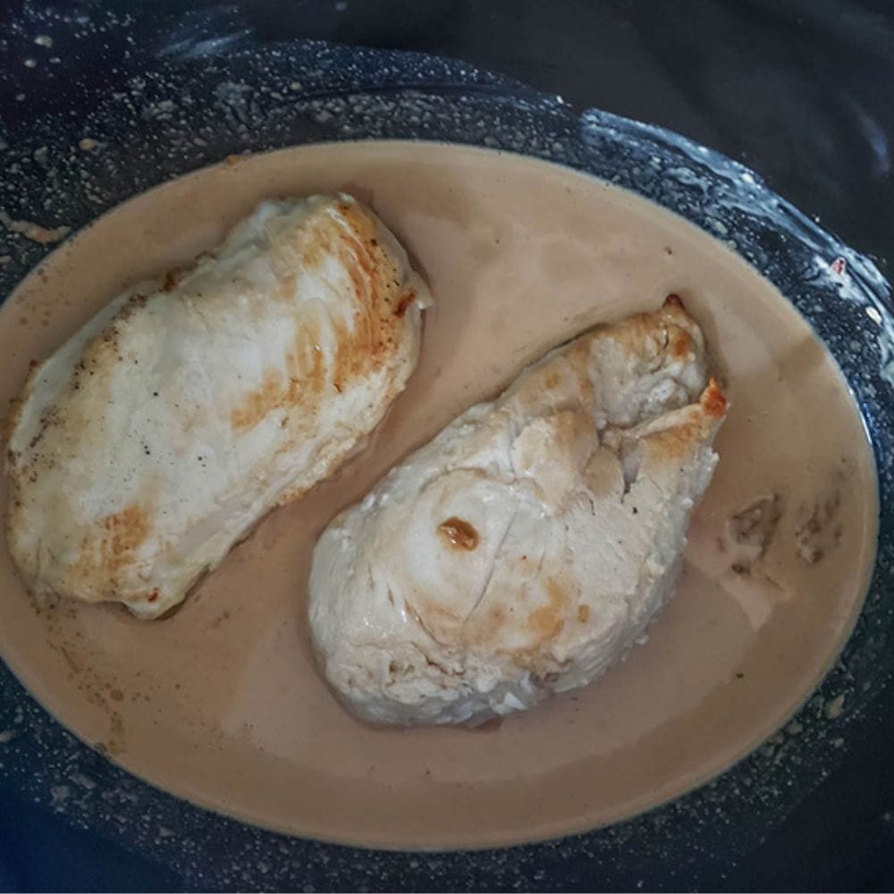 two boneless chicken breasts in a slow cooker