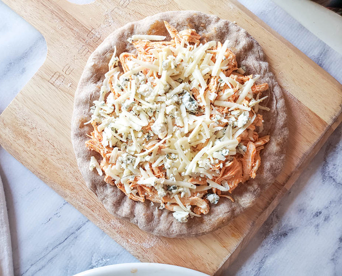 buffalo chicken topped with cheese on a flatbread not cooked