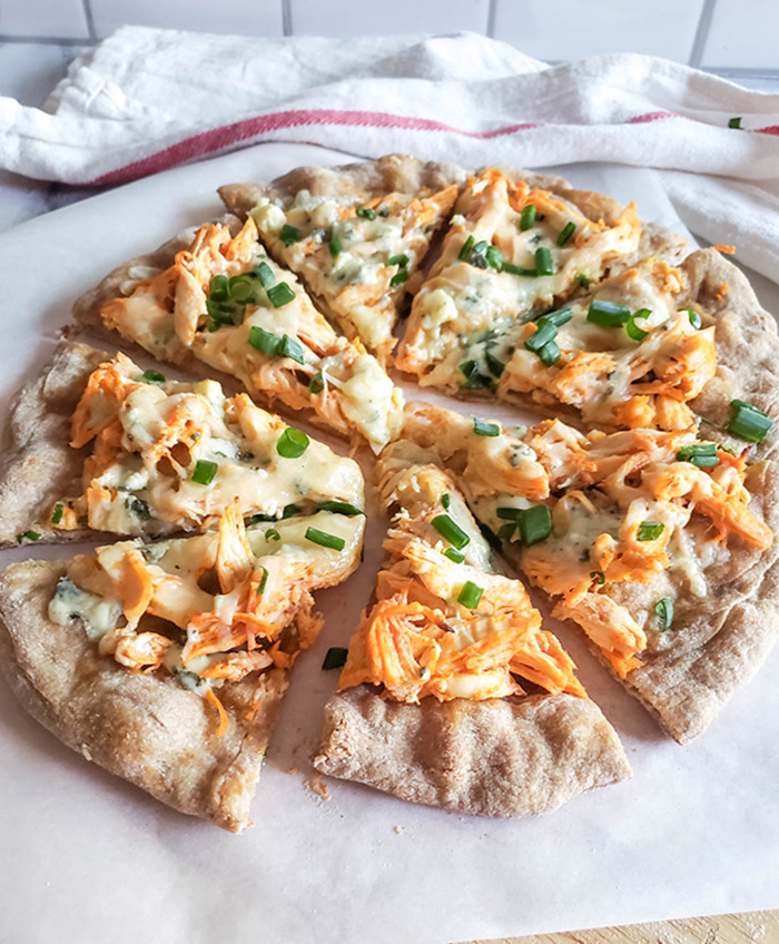 buffalo chicken pizza cooked and cut on parchment paper