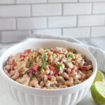 Mexican Macaroni Salad in a white serving bowl with limes on the side