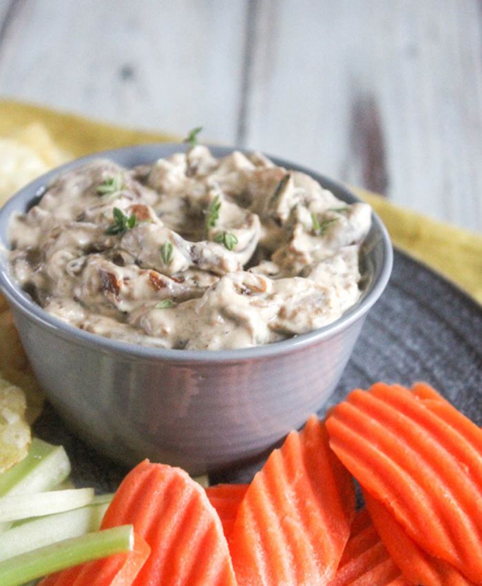 a small bowl of onion dip with chips and vegetables