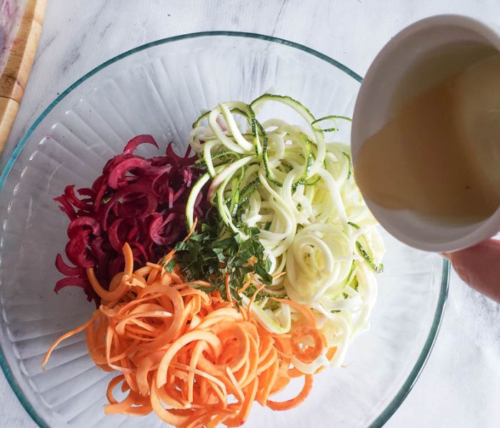 process step 3 veggie spirals with dressing pouring in