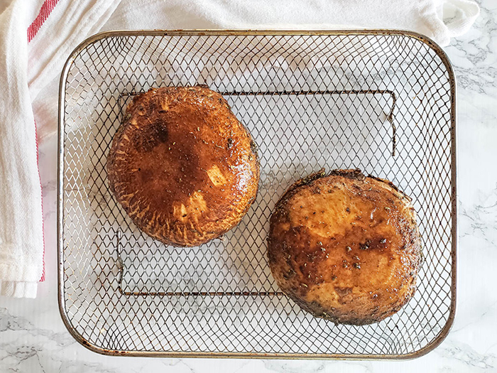 second step of process uncooked portobello mushroom on an air fryer basket