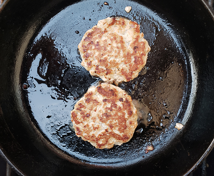 process shot of turkey burgers cooking in pan after being flipped over