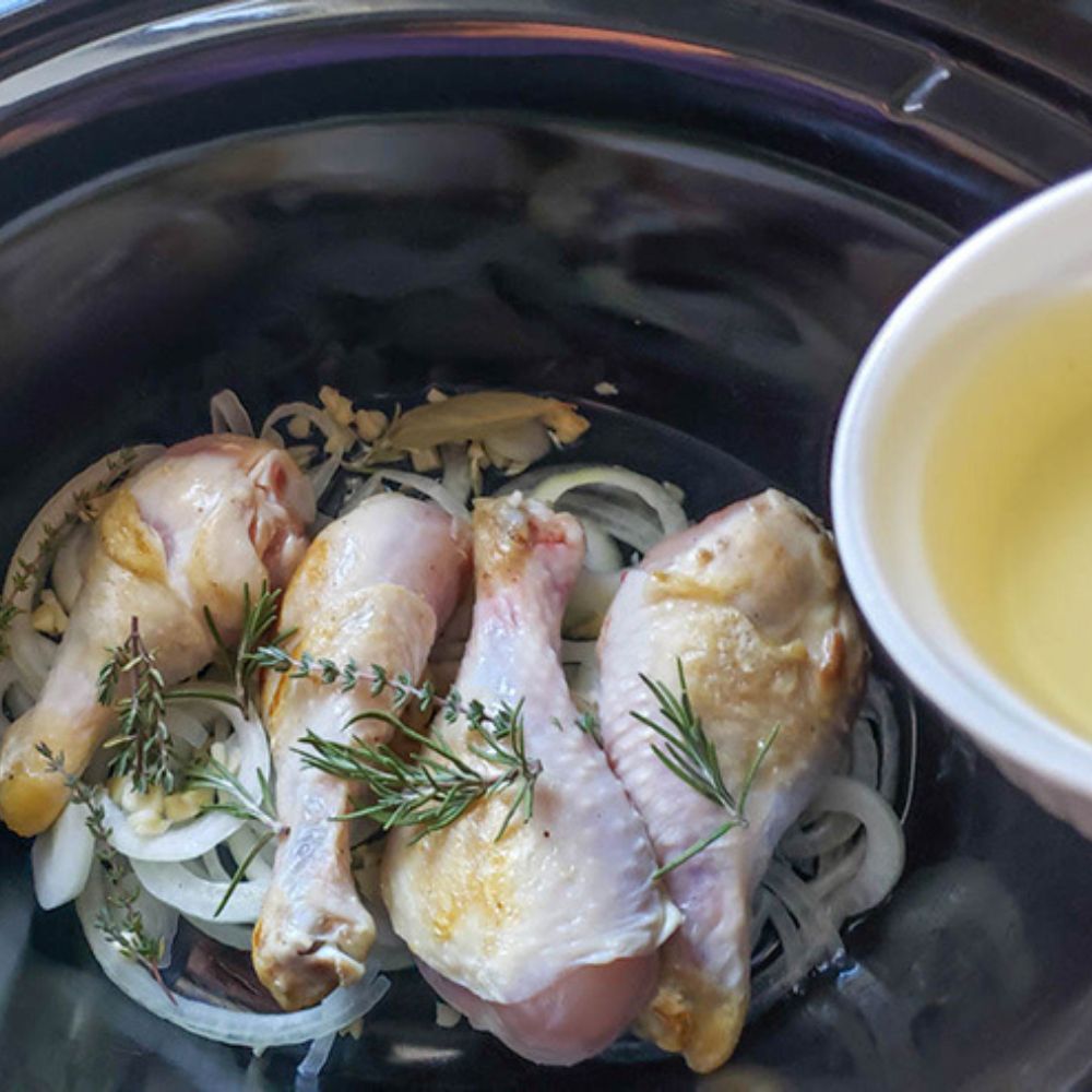 step 3 chicken legs in a slow cooker with herbs on top