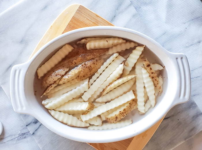 cut fries soaking in water in a white dish