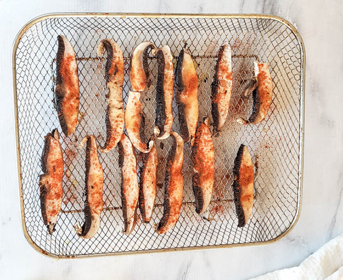 slices of portobello mushrooms on an air fryer tray