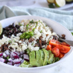 close up picture of vegetable burrito bowl with avocados, onions and jalapeno peppers on top
