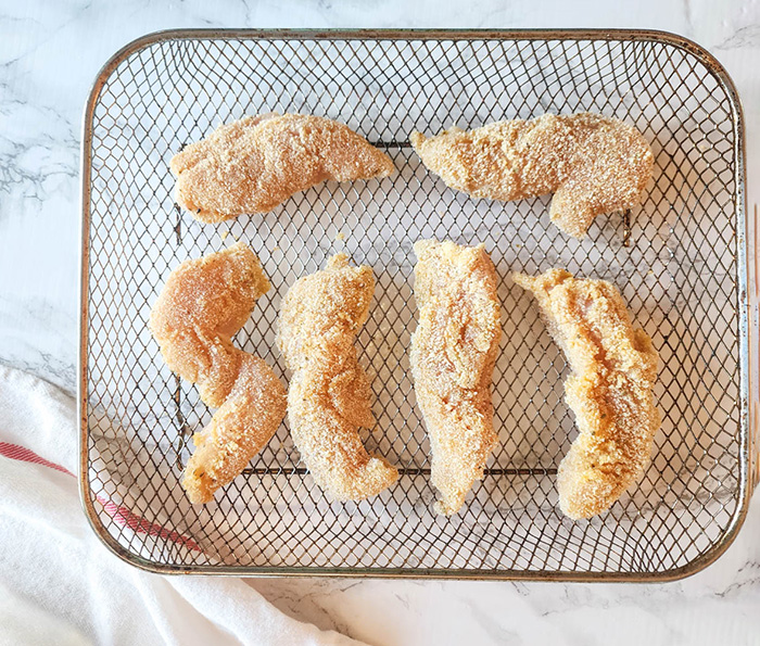 chicken tenders on air fryer tray breaded uncooked