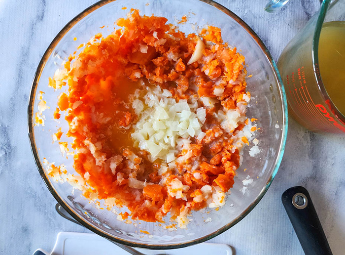 carrot and turnip mash mashed in a bowl with butter an onions added