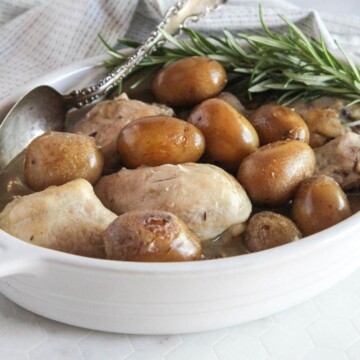 a close up picture of slow cooker chicken legs and potatoes in a white casserole dish