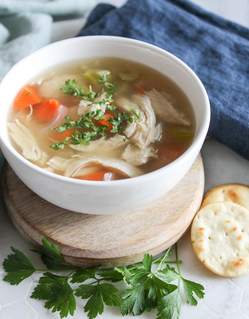chicken soup in a bowl with parsley and crackers