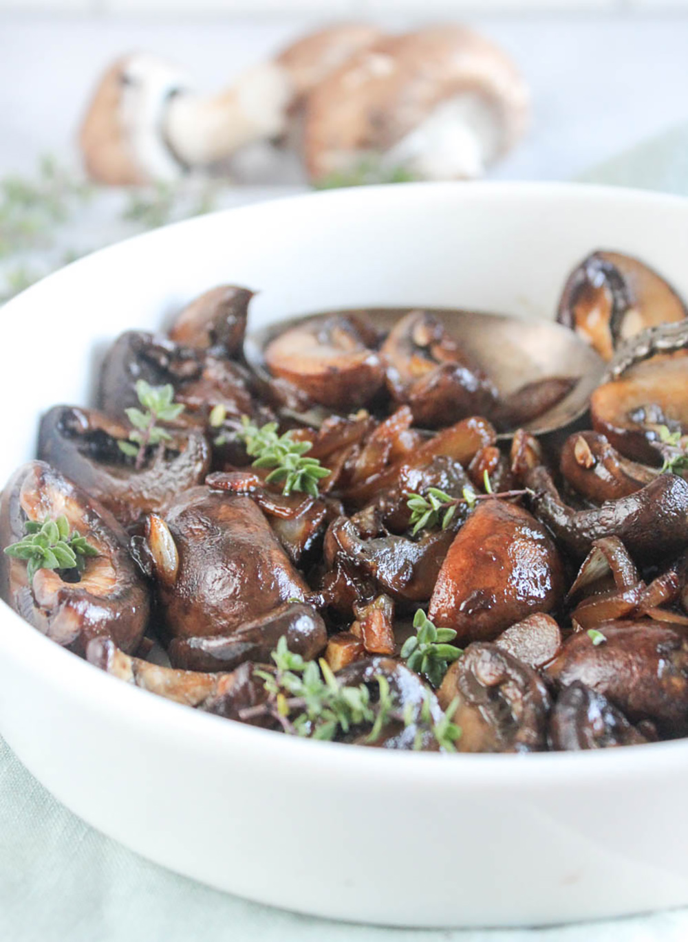 close up of balsamic mushrooms in a white serving bowl