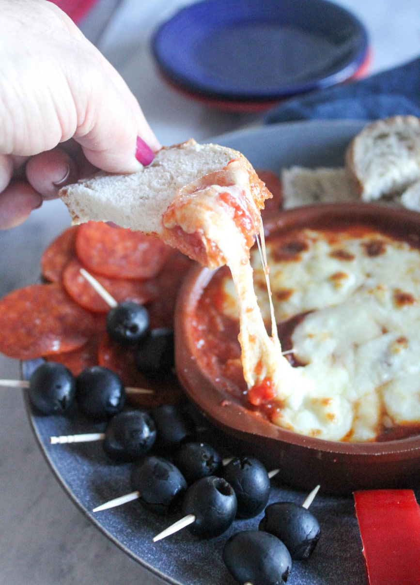 A piece of bread dipped into cheesy pizza sauce