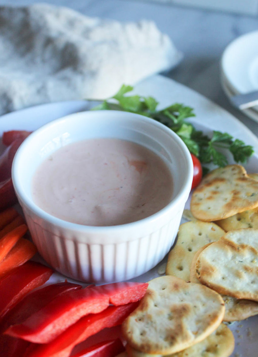 sriracha dipping sauce on a plate with veggies and crackers