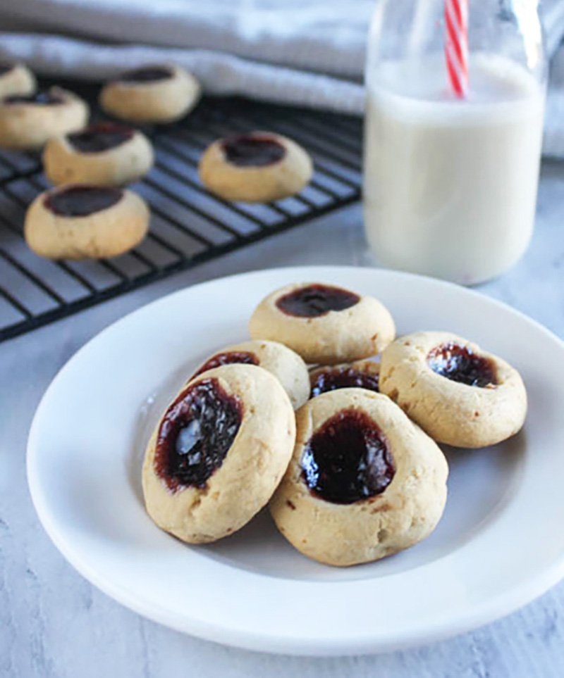 butter cookies with jam on a white plate with a milk bottle in the background
