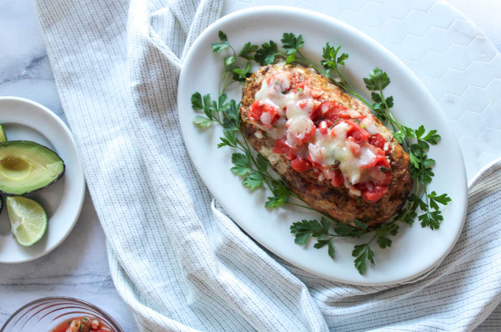 overhead view of meatloaf with cheese on top on a platter