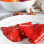a close up of two roasted peppers on a white plate