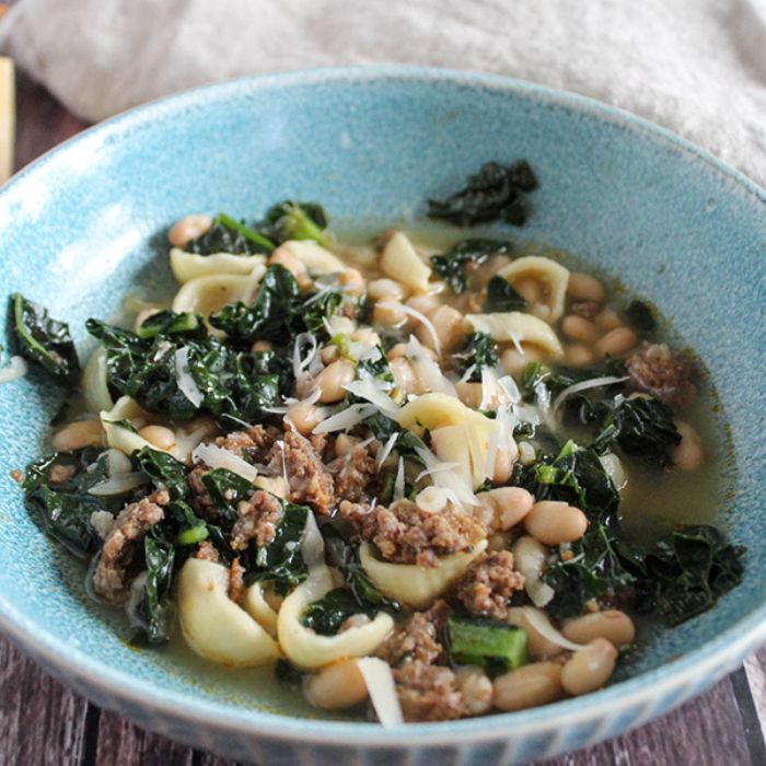 a close up picture of sausage kale soup in a bowl