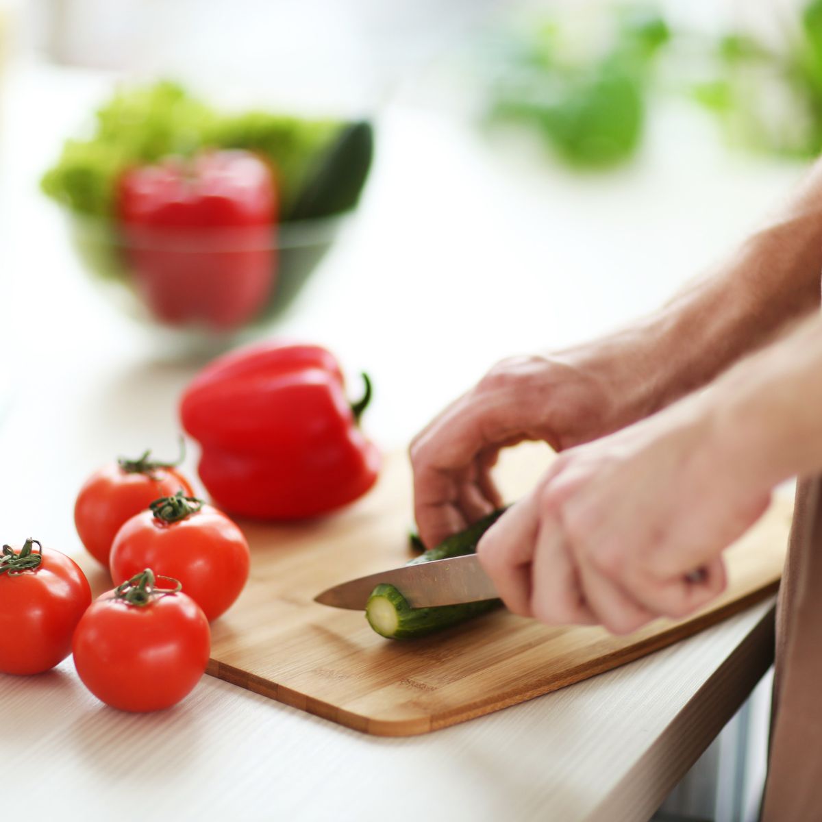 tomatoes on a board with hand cutting cucumber