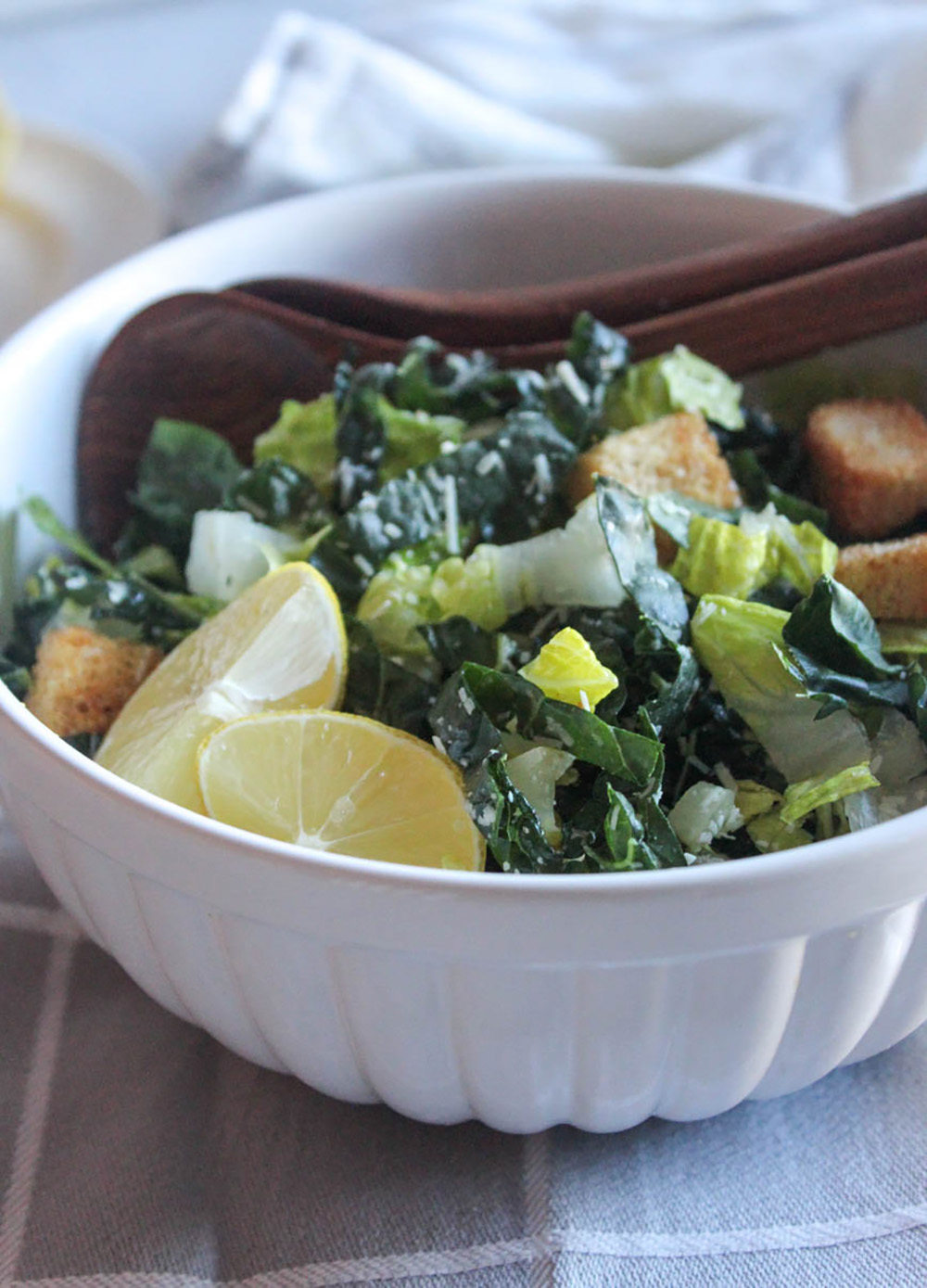 close up of kale salad in a white bowl with two spoons