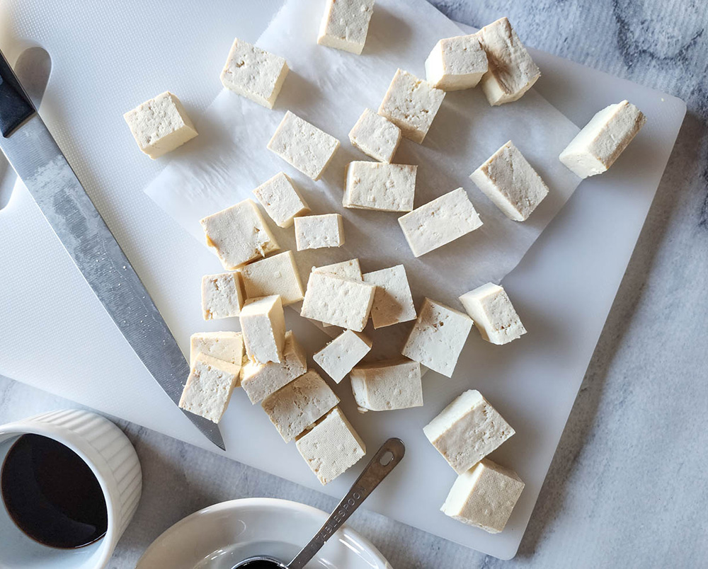 tofu cut into blocks on a white cutting board