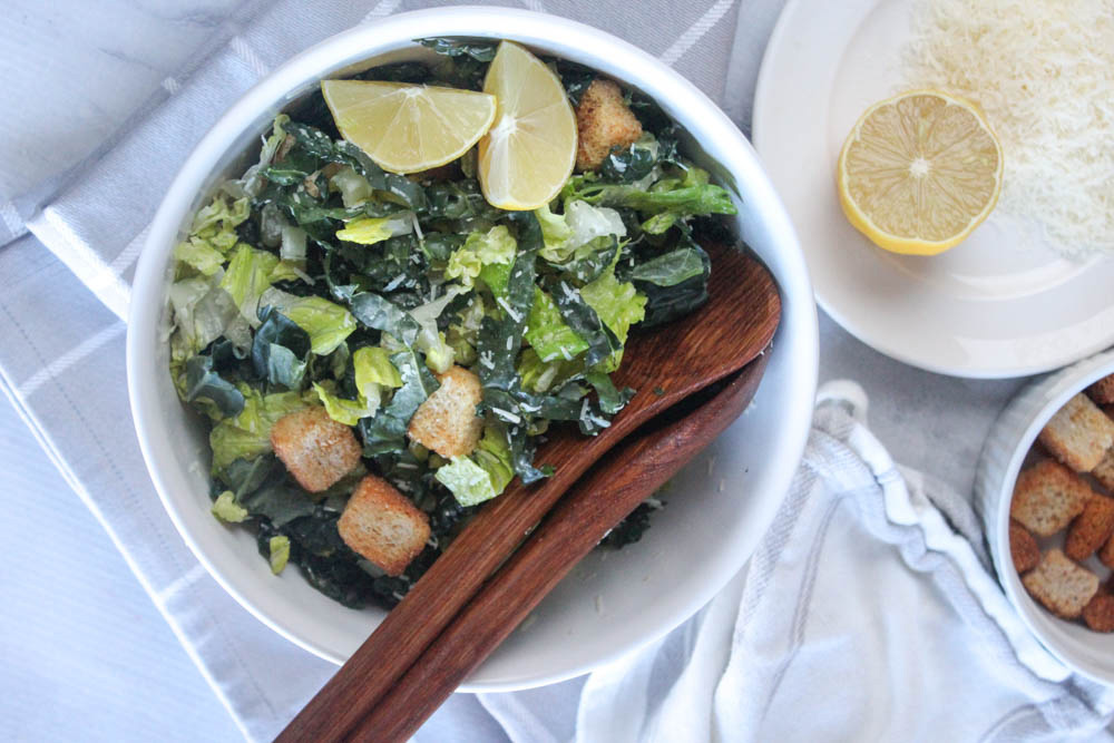 an overhead view of kale salad with wooden spoons