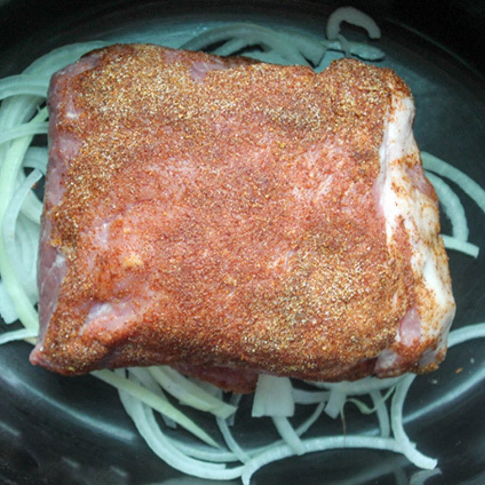 a picture of the seasoned  pork on top of sliced onions
