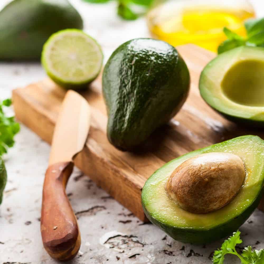 avocado cut with knife on cutting board