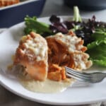 a picture of buffalo chicken lasagna cut in half on a plate with a fork and salad