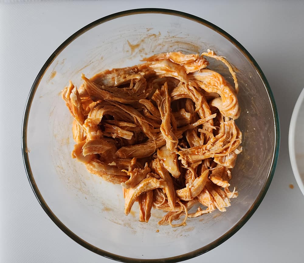 a picture of shredded chicken mixed with hot sauce
