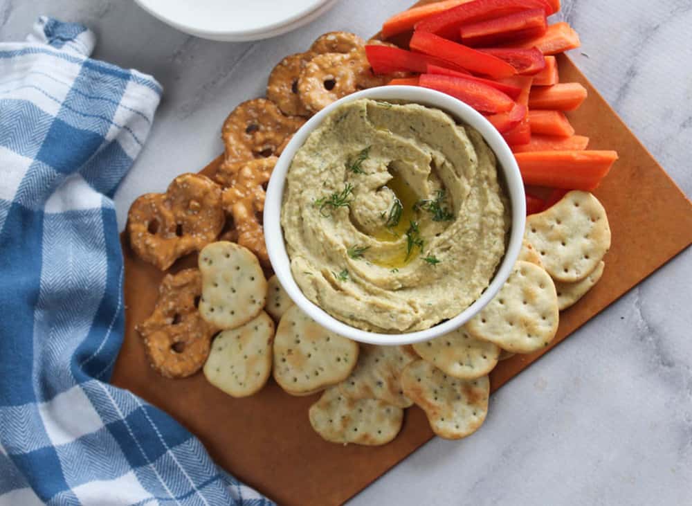 overhead view of pickle hummus with slices veggies and crackers