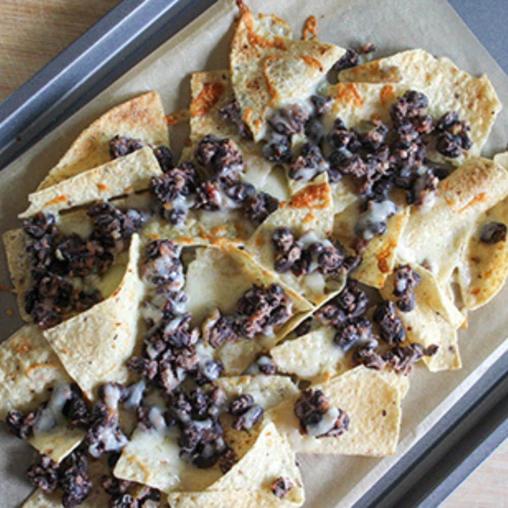 a picture of baked nachos on a sheet pan with melted cheese