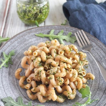 a picture of arugula basil pesto sauce on pasta on a grey plate