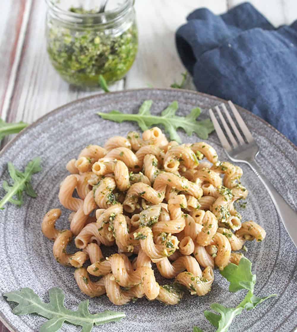 a picture of arugula basil pesto sauce on pasta on a grey plate