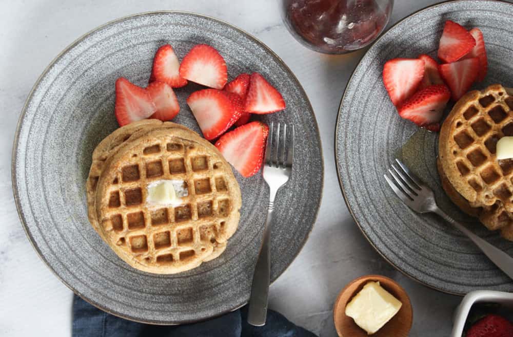 overhead picture of waffles on plates with fruit and butter