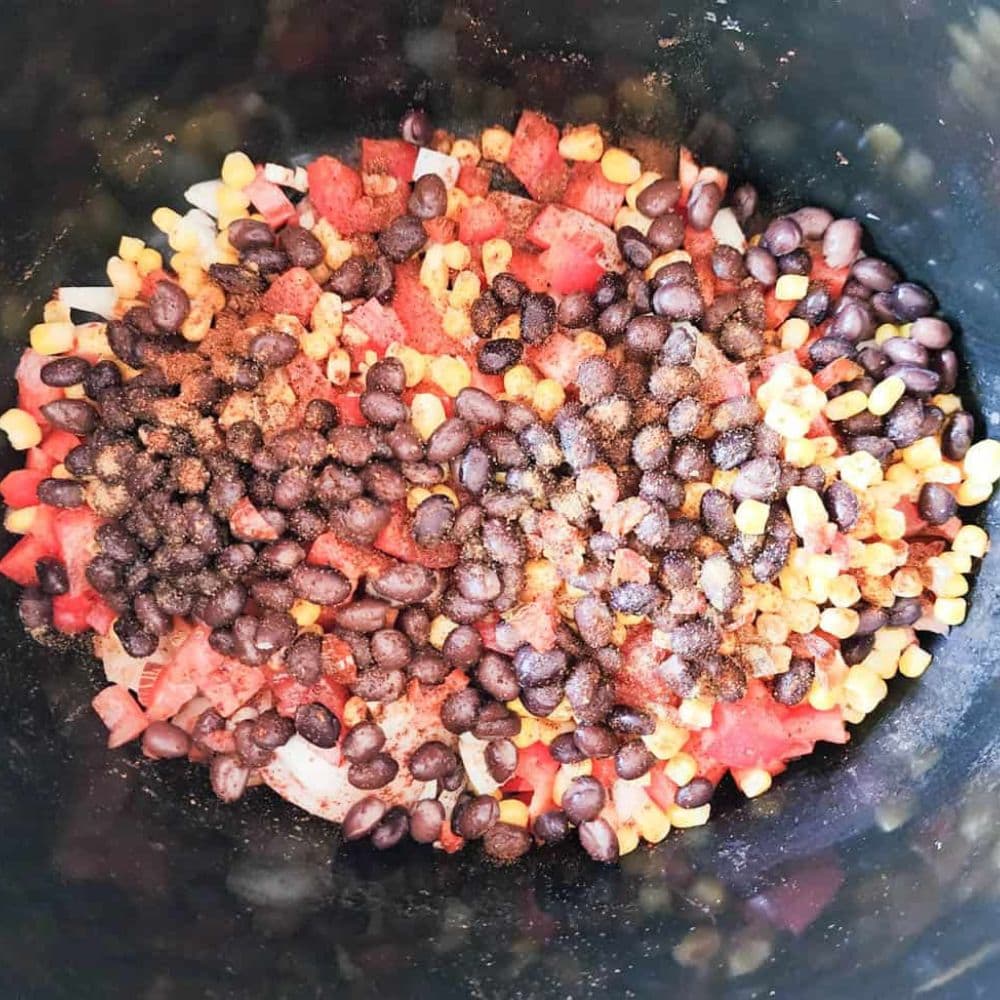 process step 2 vegetables layerd on top of two seasoned chicken breasts in a slow cooker