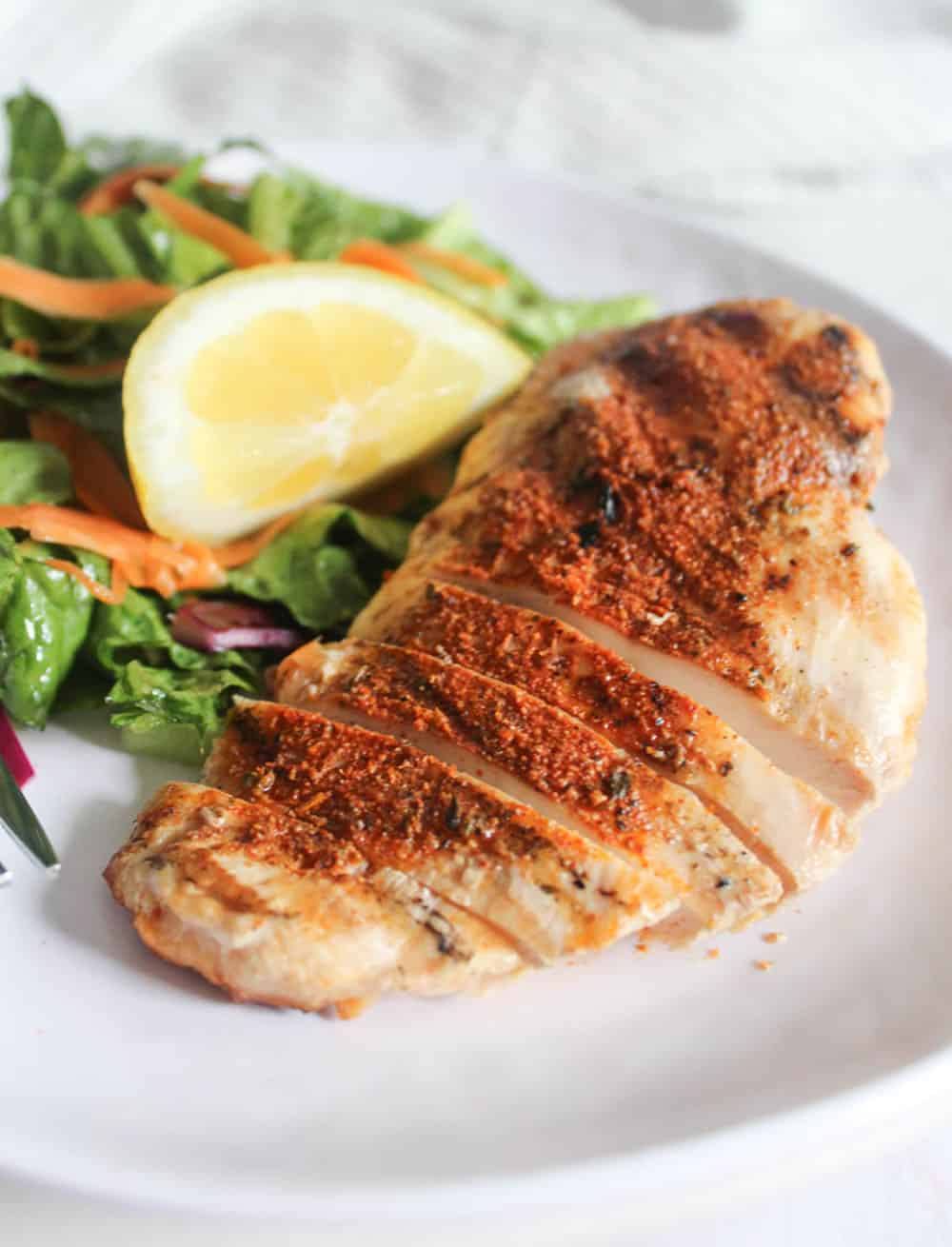 a picture of blackened chicken sliced on a plate with a salad