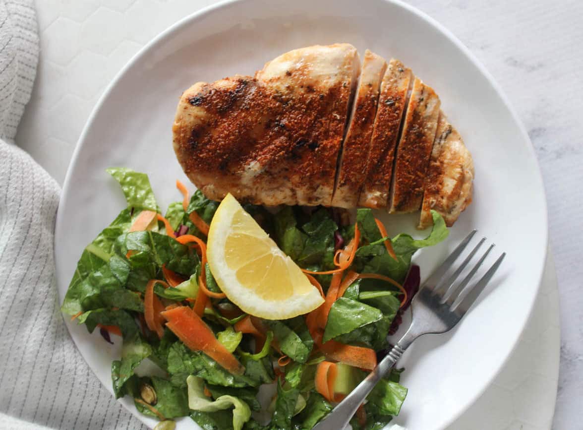 overhead view of blackened chicken breast on a plate with a salad