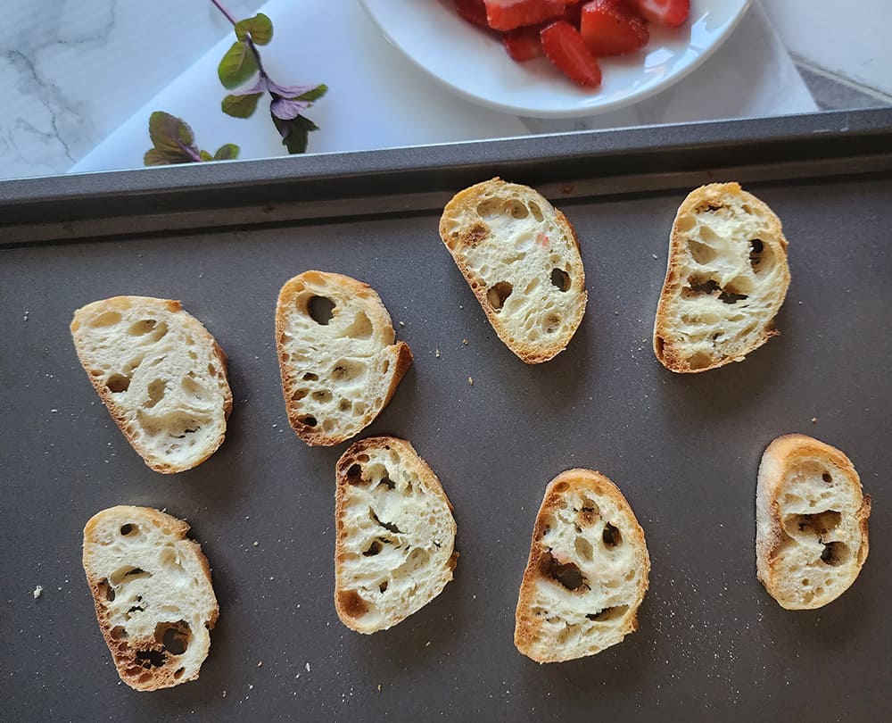 a picture of cooked baguette toast on a baking sheet