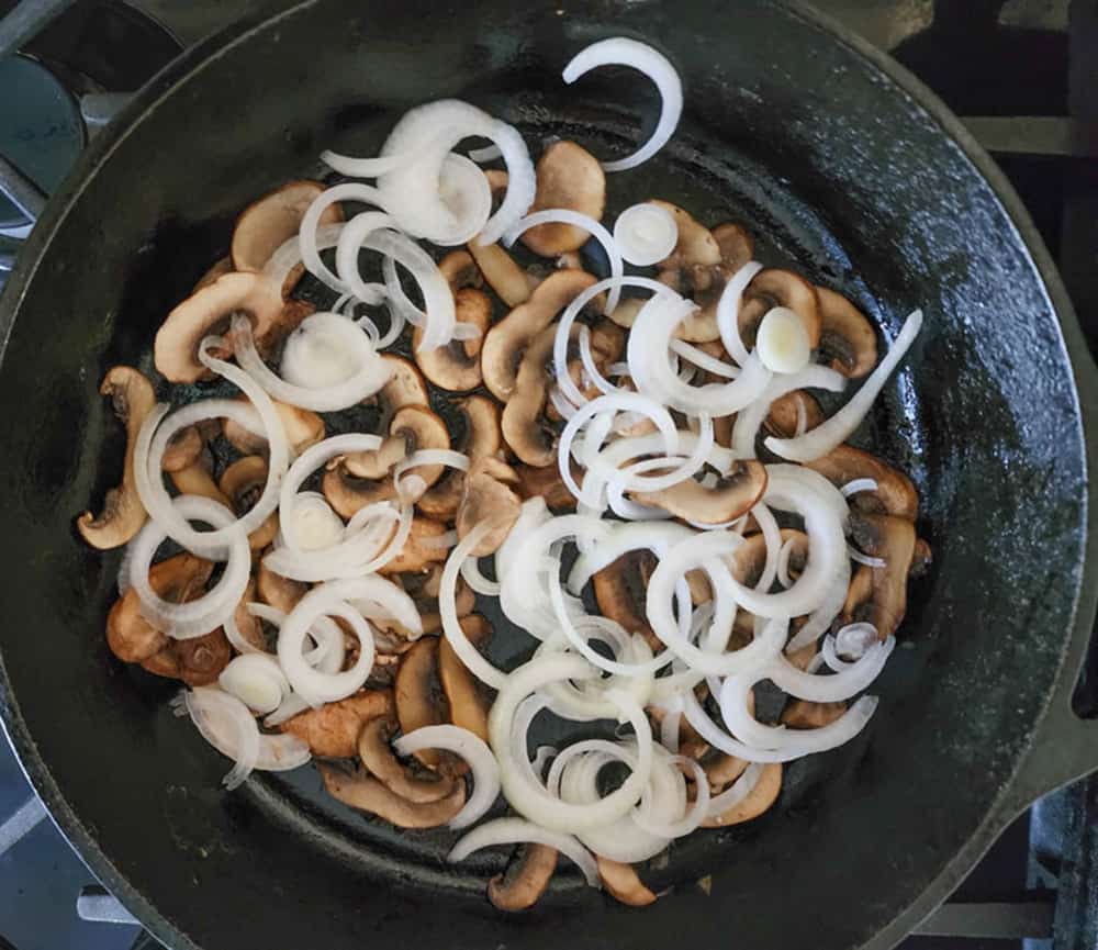 mushrooms and onions in a skillet cooking