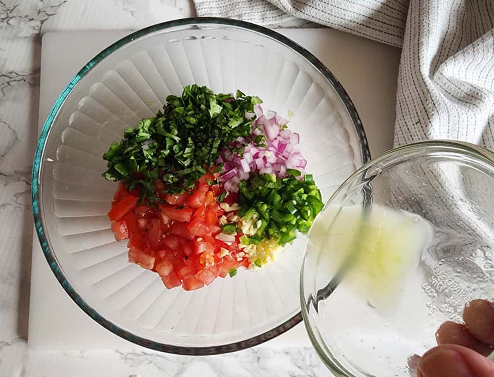 pico de gallo ingredients with lime juice pouring in