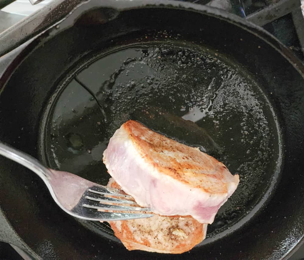 pork chops in skillet one on a fork