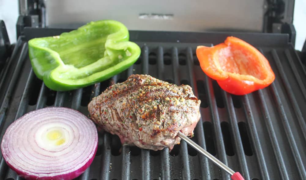 a picture of beef and peppers cooking on a grill