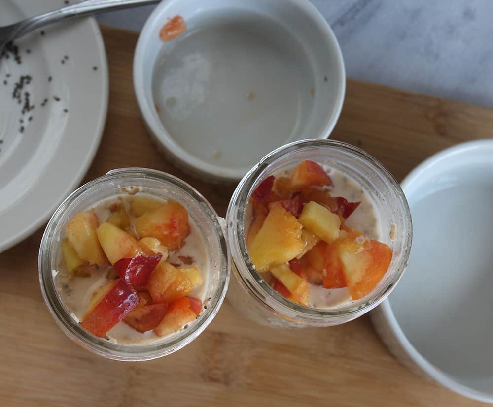 overnight oats process step 3 two jars with overnight oats mixture with diced peaches on top