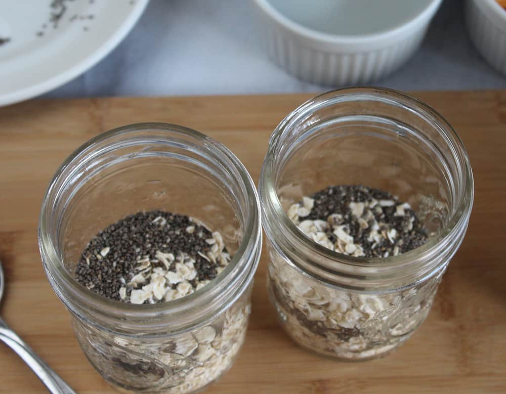 step one of overnight oats prep process; a picture of two mason jars with oats and seeds in them